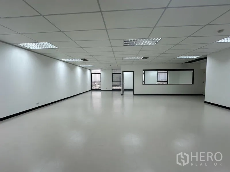 办公空间 出租 - 开放式办公室，吊顶网格灯、白色墙面与大面积采光窗。