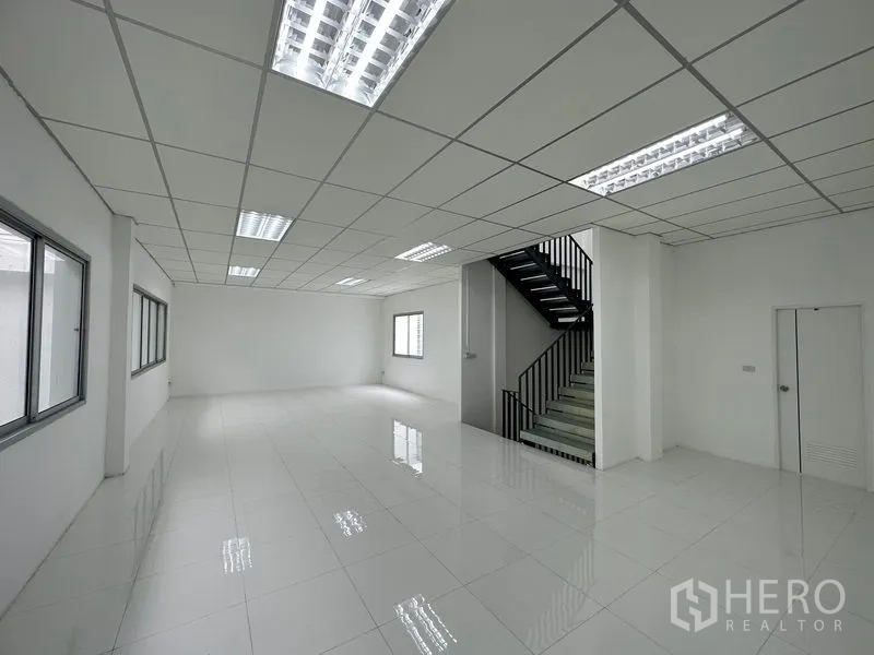 Factory for rent in Khlong Luang, Pathum Thani - Open‑plan office area with staircase and suspended fluorescent lighting