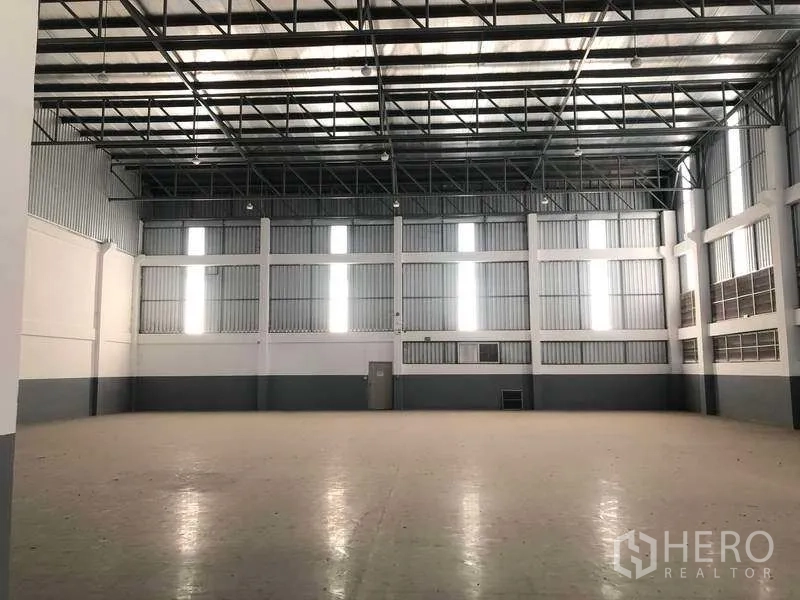 Factory for rent or sale in Bang Phli, Samut Prakan - Spacious production hall with high steel truss roof, tall windows and smooth flooring.