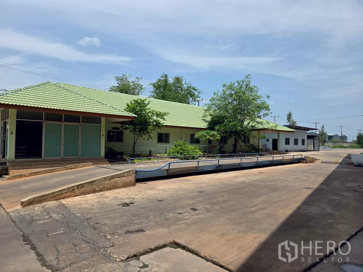 Factory for rent in Mueang Samut Sakhon, Samut Sakhon - Single‑storey admin building with green roof next to an on‑site weighbridge and broad yard.