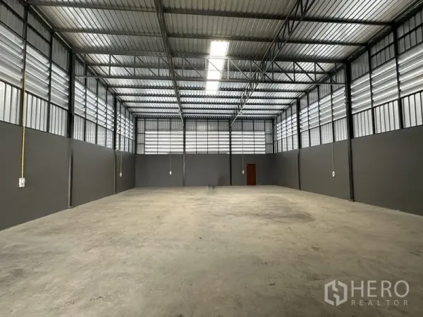Warehouse for rent in Lam Luk Ka, Pathum Thani - Spacious high-ceiling warehouse interior with steel trusses, skylight strip and power points.