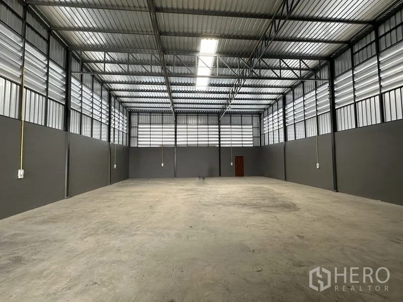 Warehouse for rent in Lam Luk Ka, Pathum Thani - Spacious high-ceiling warehouse interior with steel trusses, skylight strip and power points.