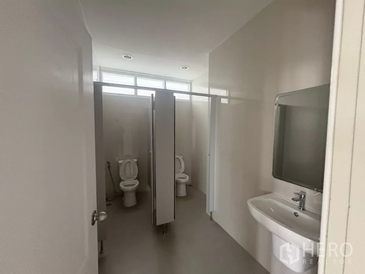 Factory for rent in Bang Phli, Samut Prakan - Clean restroom with cubicles, a sink, and upper windows for natural light.