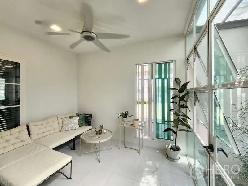 Detached House for rent or sale in Bang Phli, Samut Prakan - Bright sunroom with ceiling fan, sectional sofa and floor-to-ceiling glass.