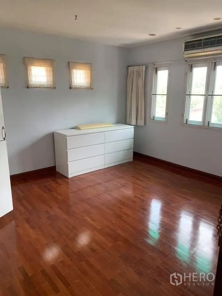Townhouse for rent in Watthana, Bangkok - Bright bedroom with polished wood floor, dresser, windows and an air conditioner.