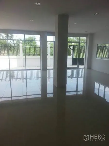 工厂 出租在Khlong Luang, Pathum Thani - 明亮的办公/展厅空间，亮面瓷砖地面，落地窗俯瞰带围栏的前院。