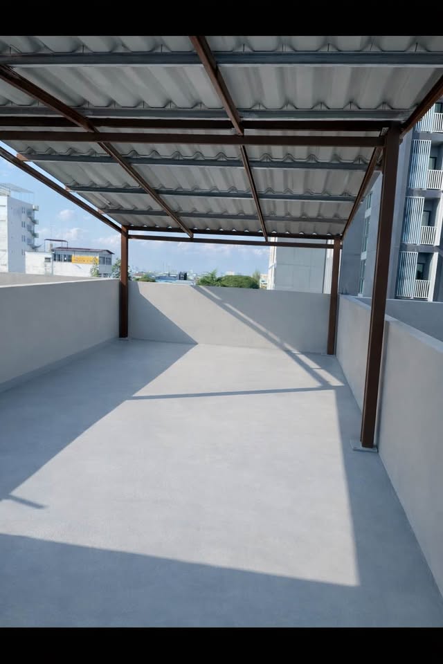 Shophouse for rent in Phra Khanong, Bangkok - Large rooftop terrace with metal canopy and parapet walls overlooking the area.