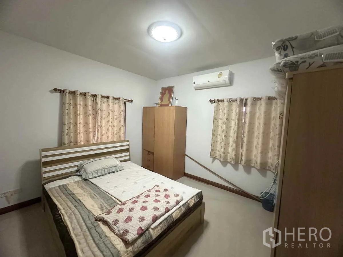 Detached House for sale in Pathum Thani - Air-conditioned bedroom with double bed, wardrobes and curtained windows.