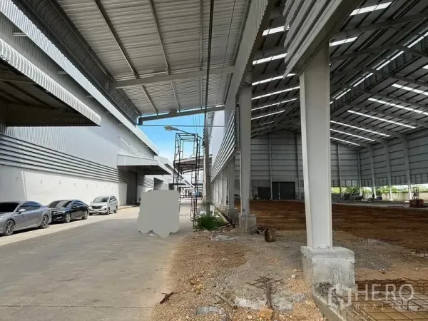 Warehouse for rent in Wang Noi, Phra Nakhon Si Ayutthaya - Covered loading bay beside a new warehouse structure with cars parked along the drive.
