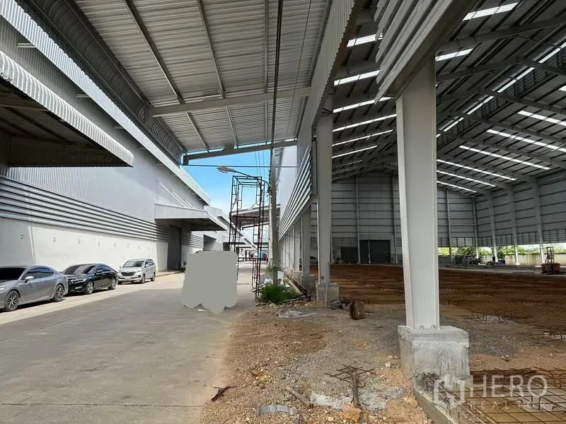 Warehouse for rent in Wang Noi, Phra Nakhon Si Ayutthaya - Covered loading bay beside a new warehouse structure with cars parked along the drive.