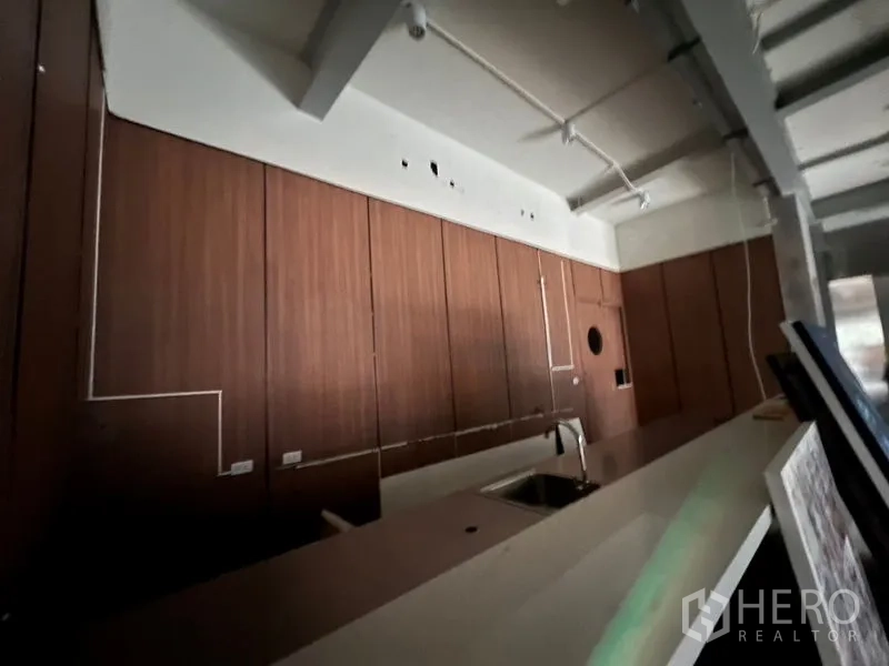 Retail Space for rent in Watthana, Bangkok - Close-up of counter with sink and wood cabinetry in a commercial shell space.