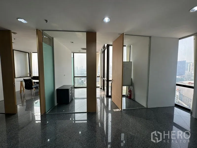 Office Space for rent - Open office corridor with private rooms, glass panels and large windows facing the city.