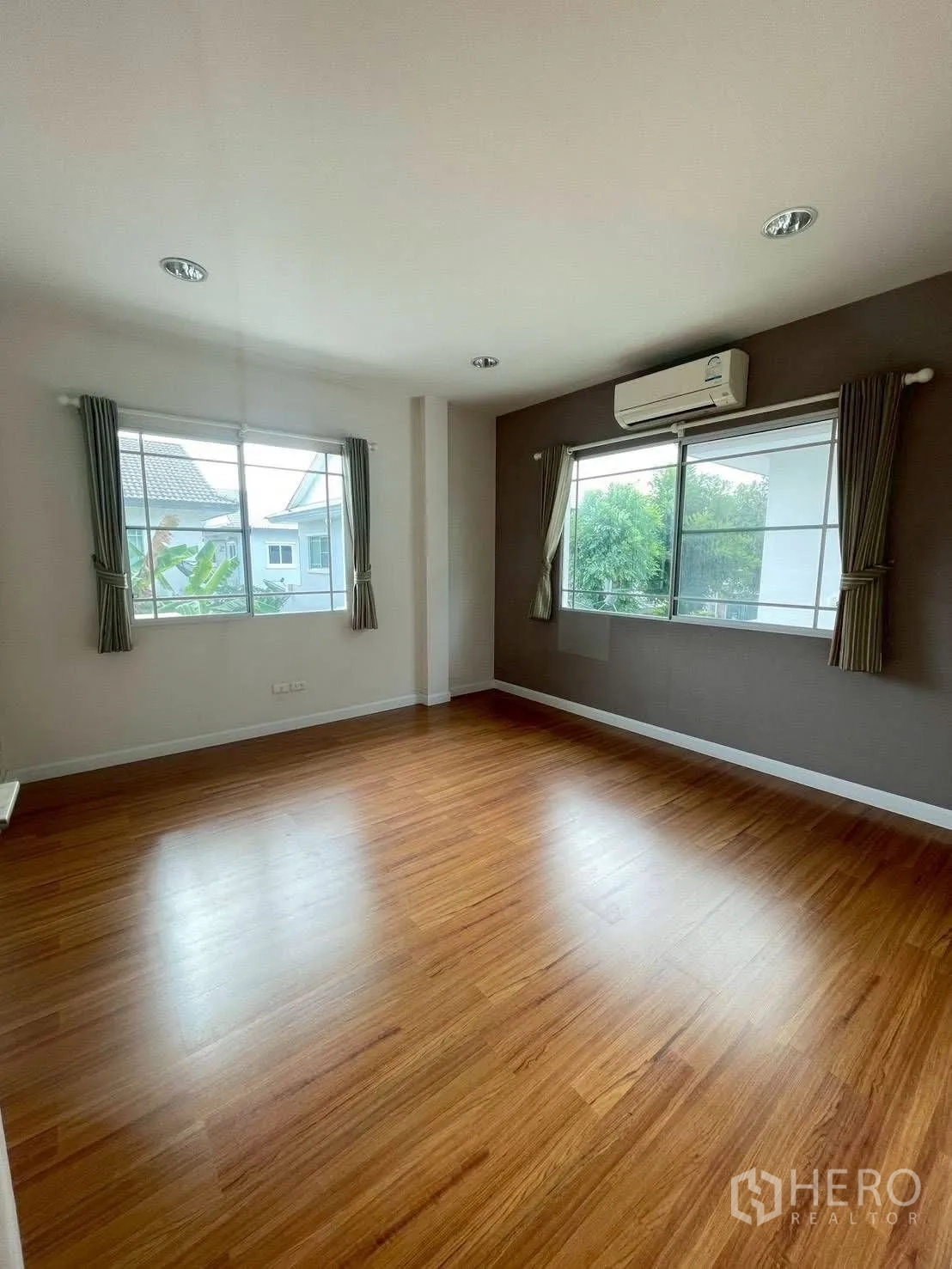 Detached House for rent or sale in Mueang Samut Prakan, Samut Prakan - Corner bedroom with large windows, wood floors, neutral walls and air conditioner.