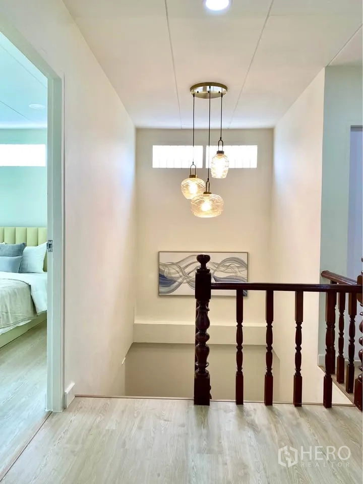 Detached House for rent in Huai Khwang, Bangkok - Stair landing with pendant lights, artwork and wooden railing.
