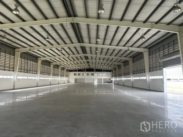 Factory for rent in Phra Nakhon Si Ayutthaya - Long-span production hall with high-bay lights, ridge ventilation, and roller shutter at the far end.