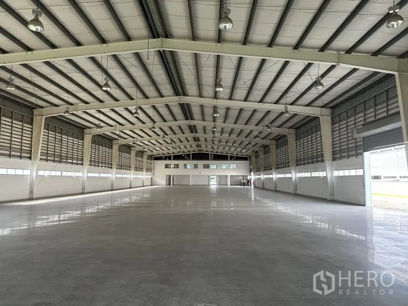 Factory for rent in Phra Nakhon Si Ayutthaya - Long-span production hall with high-bay lights, ridge ventilation, and roller shutter at the far end.