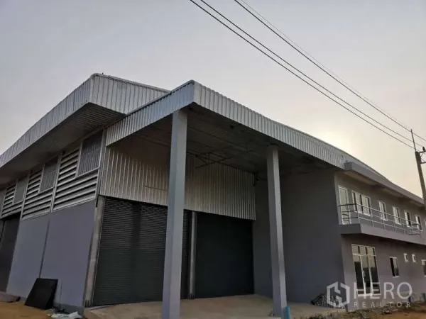 Warehouse for rent in Khlong Luang, Pathum Thani - Modern warehouse exterior with covered loading bay, roller shutters and attached office block in Khlong Luang.