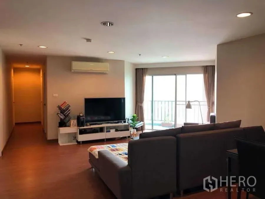 Condominium for sale in Huai Khwang, Bangkok - Open-plan living area with air conditioning, TV unit and access to the balcony.