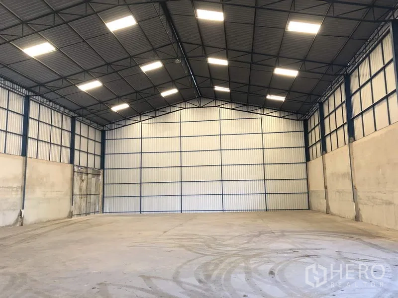 Warehouse for rent in Pathum Thani - Spacious high-ceiling warehouse interior with steel frame, bright LED lighting and smooth concrete floor.