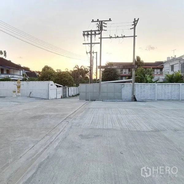 Warehouse for rent in Prawet, Bangkok - Wide gated entrance and expansive concrete yard in front of the property.