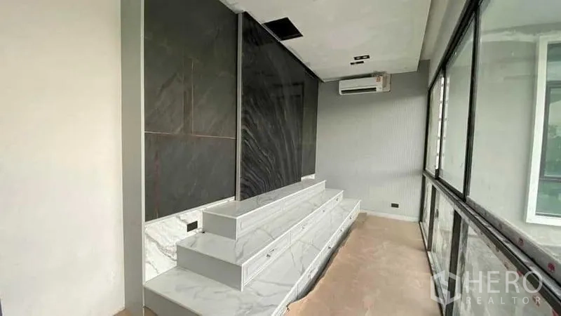 Detached House for sale in Mueang Nonthaburi, Nonthaburi - Marble TV console and dramatic black stone feature wall beside large windows and air conditioning.