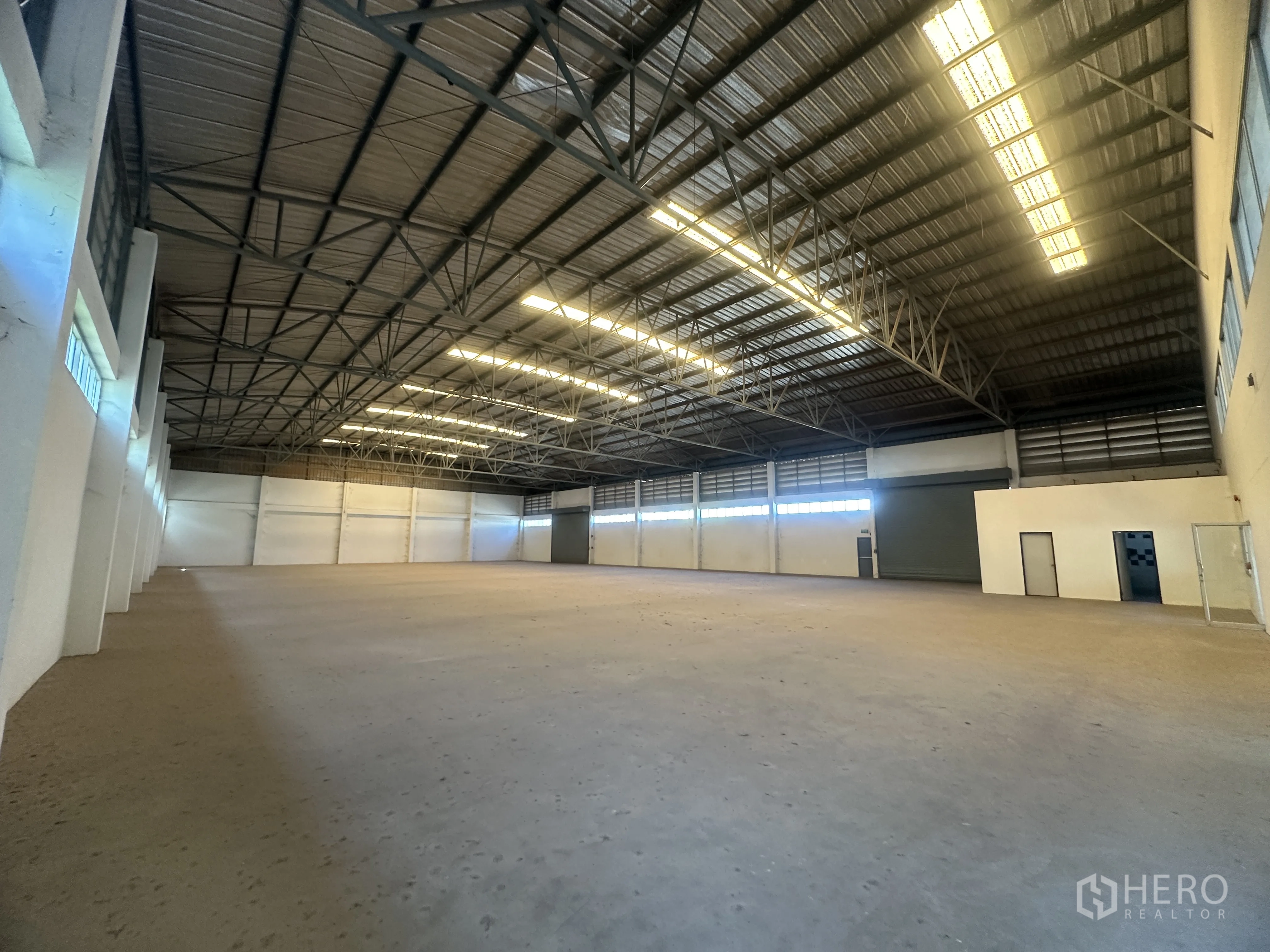 Factory for rent in Bang Pa-in, Phra Nakhon Si Ayutthaya - Warehouse interior featuring multiple roller shutter doors, internal service rooms, and high ceiling.