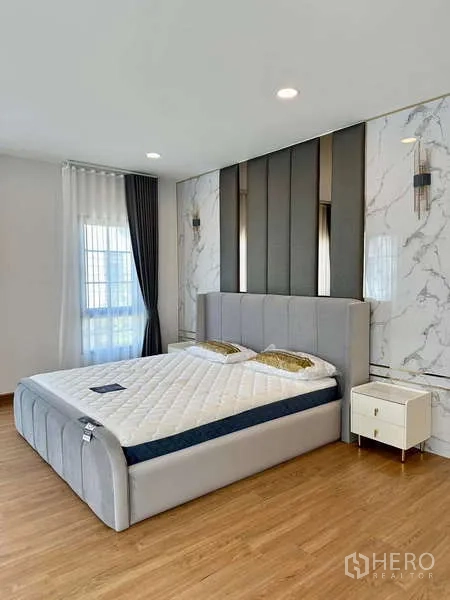 Detached House for rent in Bang Phli, Samut Prakan - Elegant bedroom with marble accent wall, upholstered headboard and bedside lighting.
