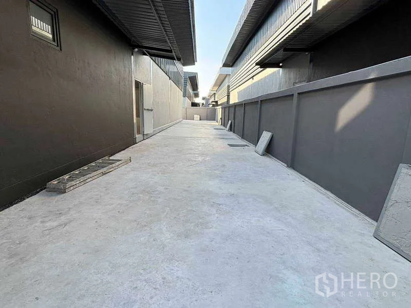 Factory for rent in Bang Bo, Samut Prakan - Wide concrete service lane running between warehouse blocks for easy truck movement.
