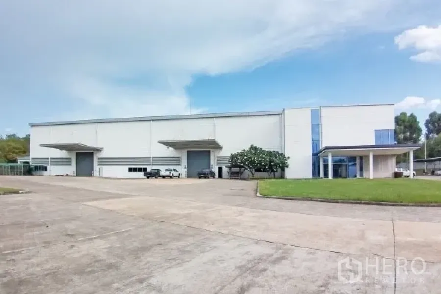 Factory for sale in Rayong - Modern white factory exterior in Pluak Daeng, Rayong with two loading bays, office wing, wide driveway and lawn.