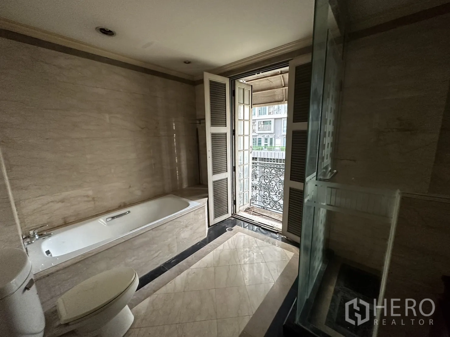 Home Office for rent in Huai Khwang, Bangkok - Bathroom opening to a balcony with wrought-iron railing beside tub and shower.
