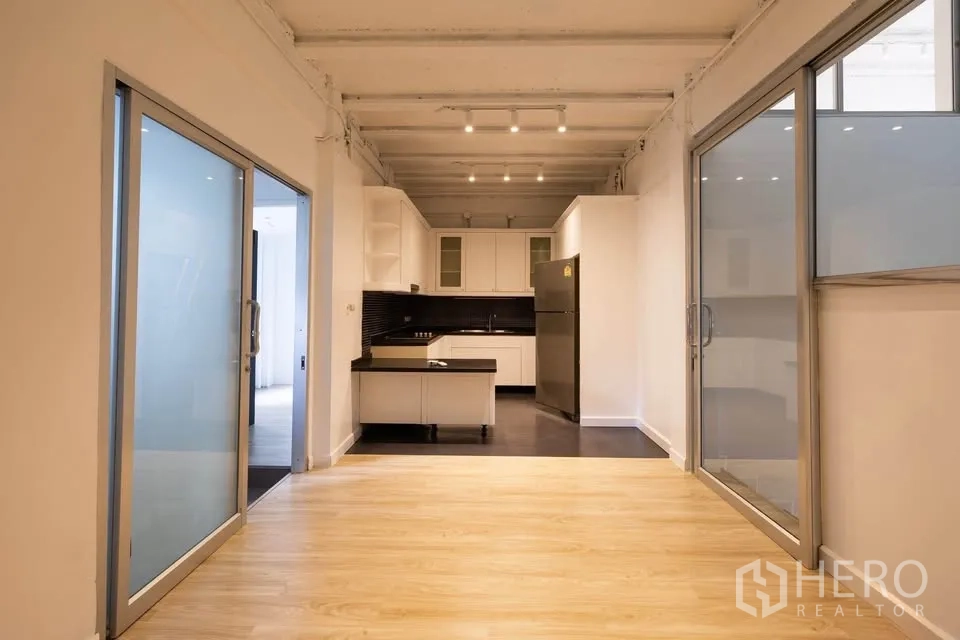 Townhouse for rent in Khlong Toei, Bangkok - Dining space facing a modern kitchen, framed by sliding glass doors on both sides.