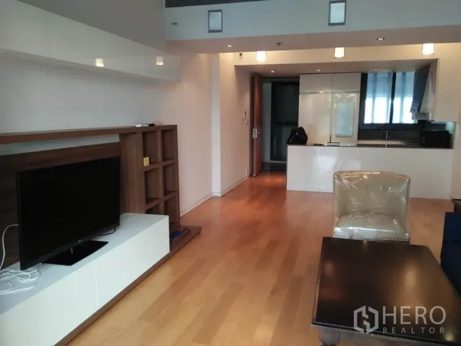 Condominium for rent in Sathon, Bangkok - Living room with TV console, shelving and view toward the kitchen in a Bangkok condominium.