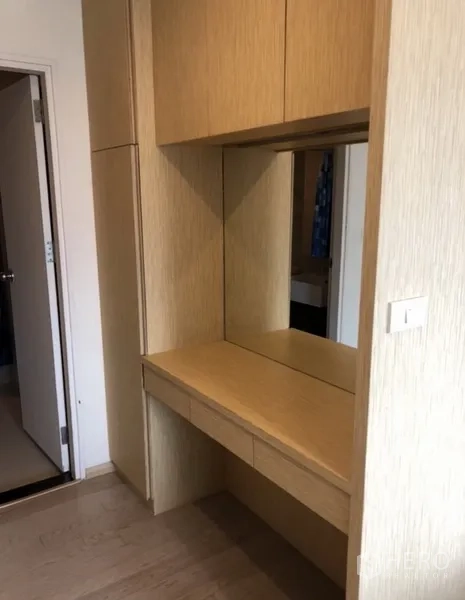 Condominium for rent in Khlong Toei, Bangkok - Built-in vanity with mirror, drawers and overhead storage in light wood.