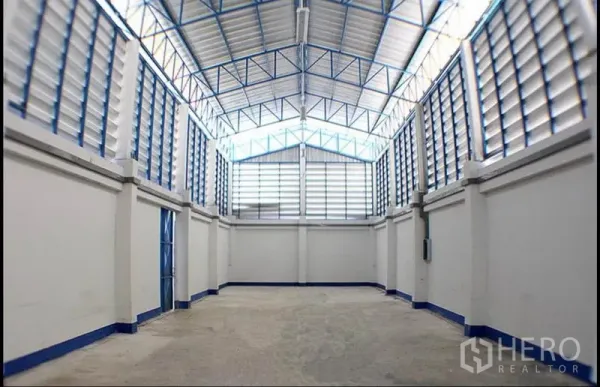 Factory for rent in Pak Kret, Nonthaburi - High-ceiling warehouse hall with steel trusses, louvered ventilation and concrete floor.