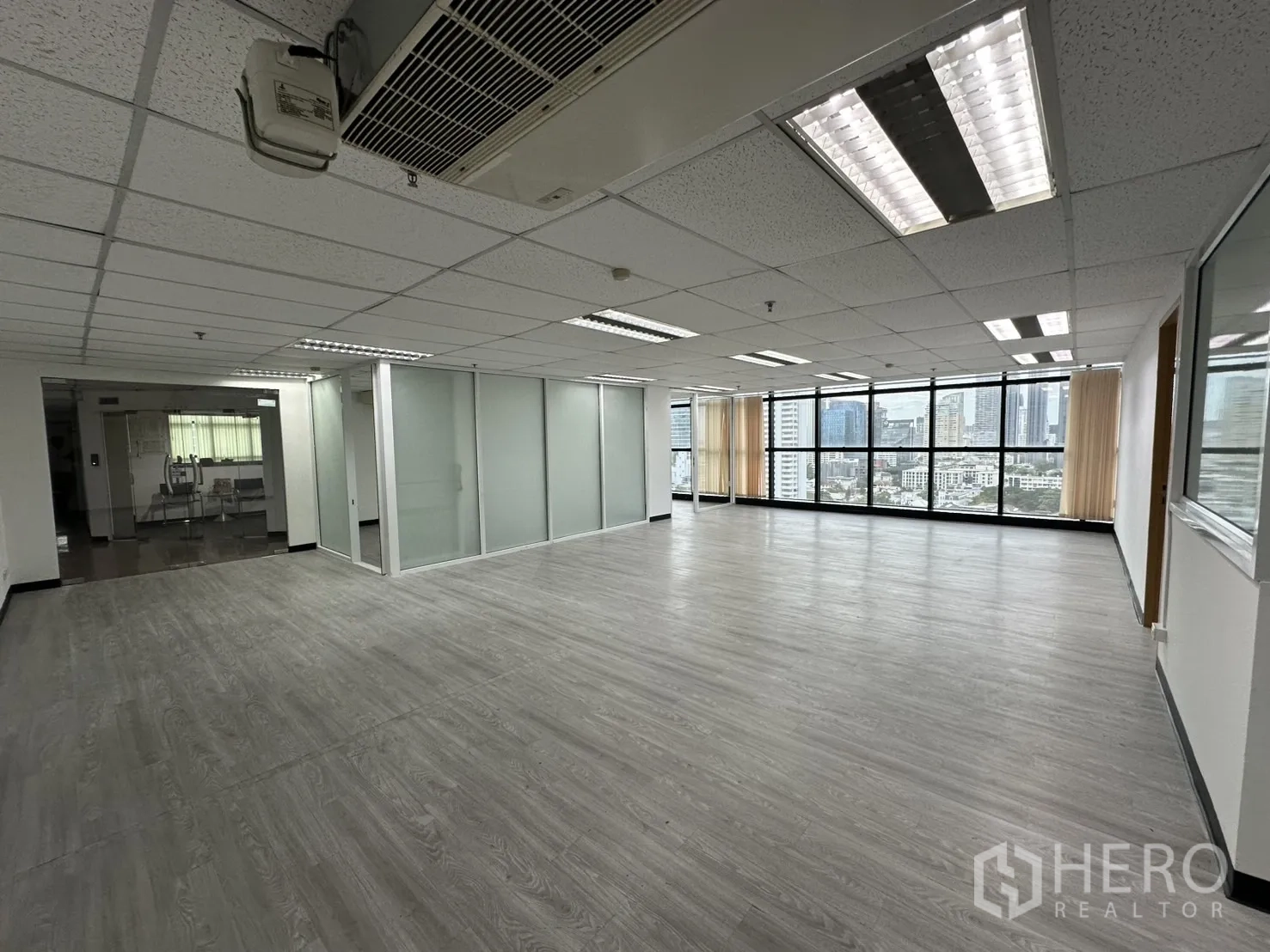 Office Space for rent in Watthana, Bangkok - Bright office interior with wood-look floors, ceiling lights, glass partitions and skyline views in Watthana.