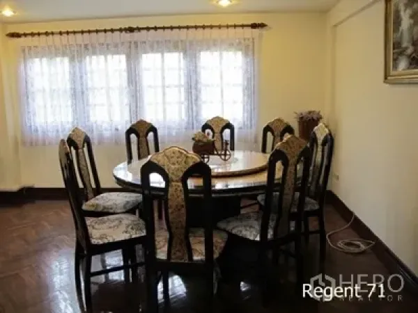 Townhouse for rent in Khlong Toei, Bangkok - Dining room with a round table and eight upholstered chairs beside curtained windows.