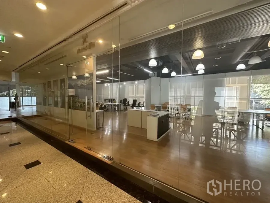 Office Space for rent in Pathum Wan, Bangkok - Open-plan workspace seen through full-height glass frontage from the corridor.