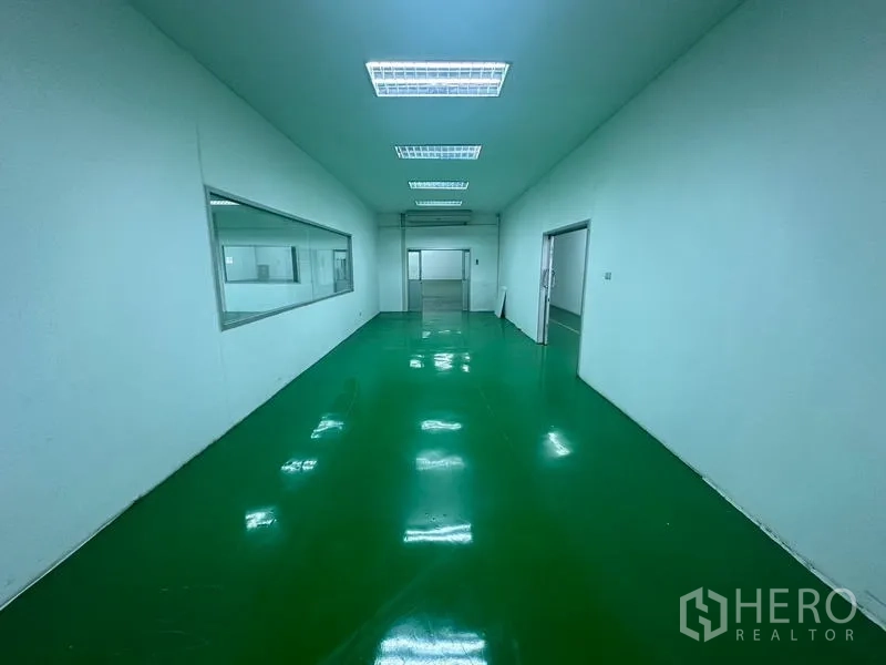 Warehouse for rent in Suan Luang, Bangkok - Clean production corridor with glossy green epoxy floor and bright ceiling lights.