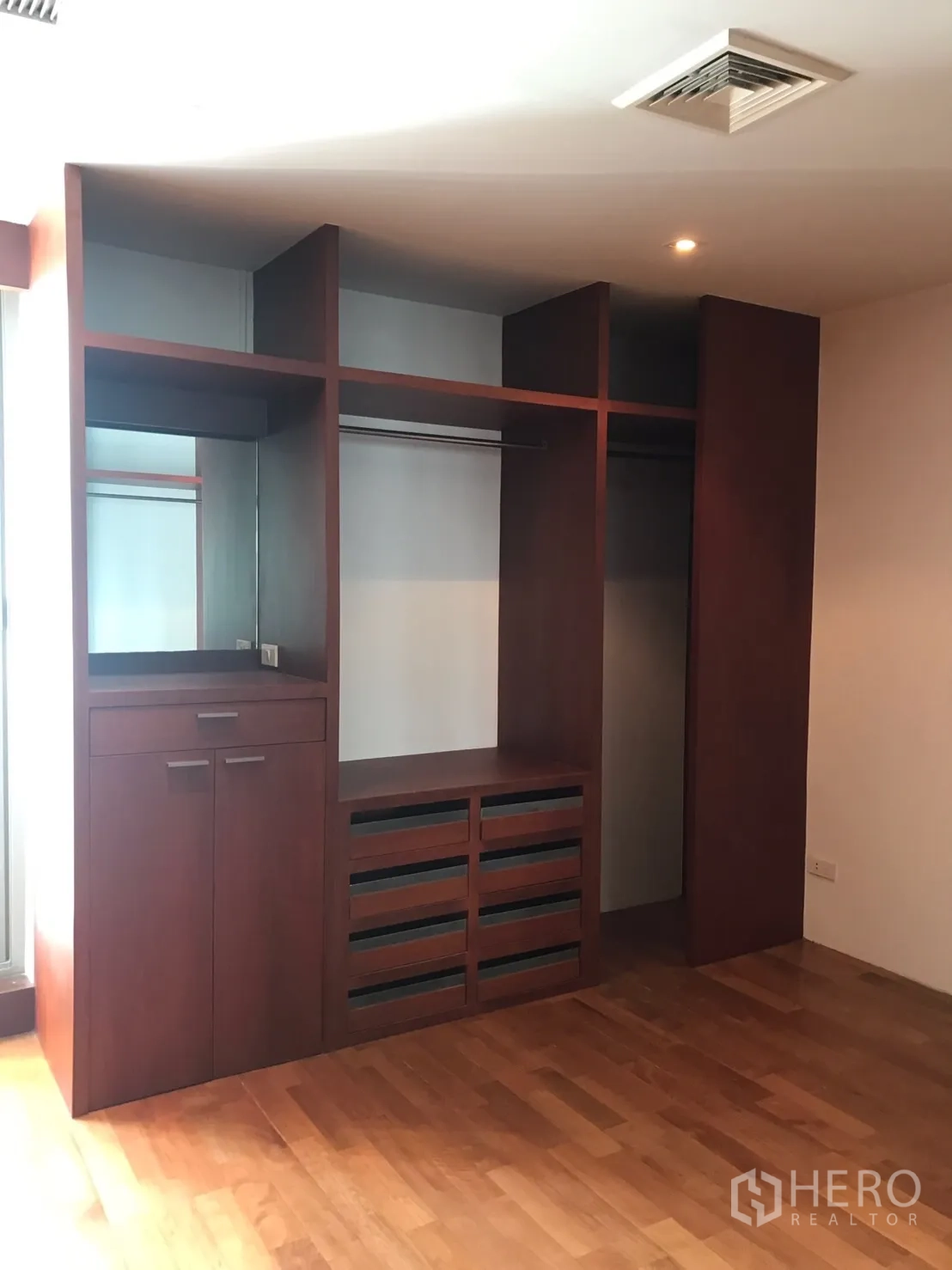 Home Office for rent in Watthana, Bangkok - Built-in wooden wardrobe and shelving in a bedroom with hardwood flooring.