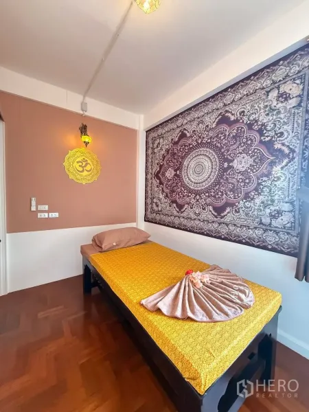 Shophouse for rent in Bang Rak, Bangkok - Private massage room with single bed, patterned tapestry wall, warm lighting, and parquet floor.