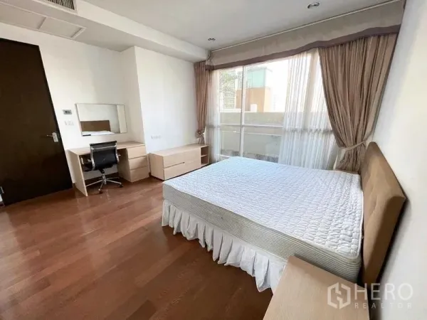 Condominium for rent in Pathum Wan, Bangkok - Spacious bedroom with large window, desk and wood floors in Pathum Wan condominium.