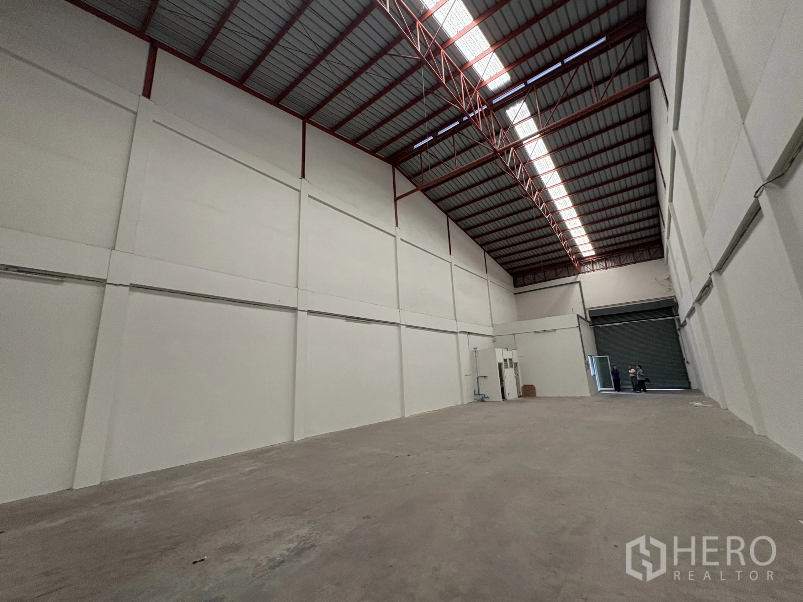 Factory for rent in Phra Samut Chedi, Samut Prakan - Wide warehouse interior facing the roller door, high-clearance steel truss roof.