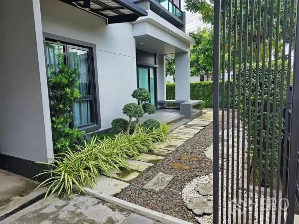 Detached House for rent or sale in Lam Luk Ka, Pathum Thani - Front garden with trimmed shrubs, stone walkway and shaded porch