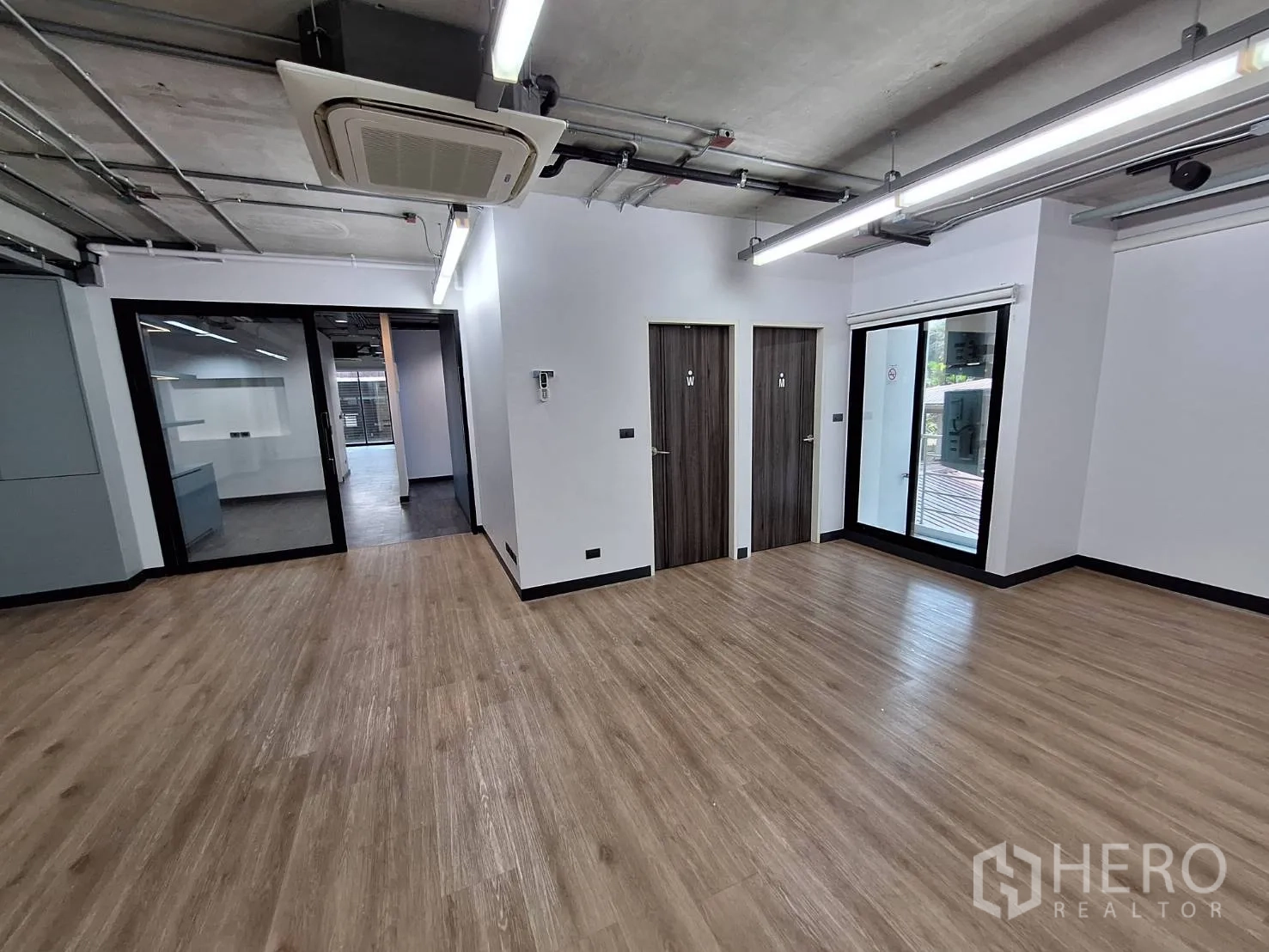 Office Space for rent - Open-plan area with two restrooms, balcony doors and cassette AC units.