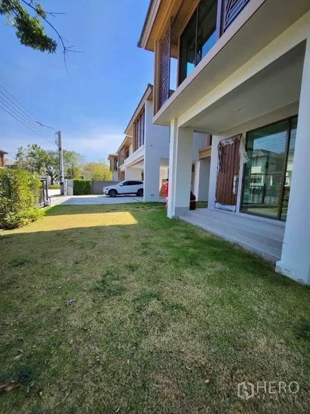 独立式住宅 出售在Sai Mai, Bangkok - 房前草坪与带顶露台，可见大幅推拉玻璃门。