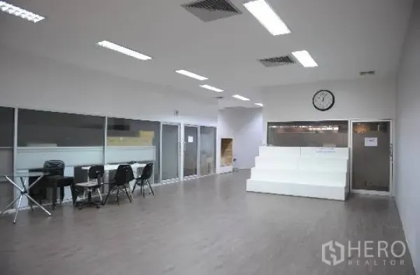 Office Space for rent in Khlong Toei, Bangkok - Open-plan office with wood floors, ceiling lights, glass partitions, and a reception platform.
