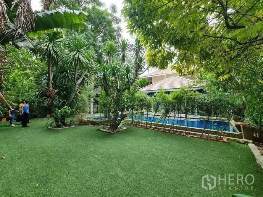Detached House for sale in Bang Na, Bangkok - Lush lawn and tropical garden with a view of the swimming pool and pavilion.