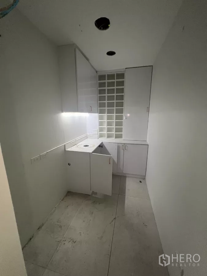 Retail Space for rent - White kitchenette with cabinets, counter and sink on tiled floor.