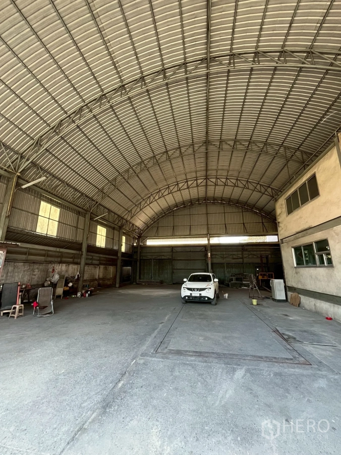 Factory for rent in Phra Pradaeng, Samut Prakan - Wide open warehouse bay with concrete floor, metal structure and parked car.