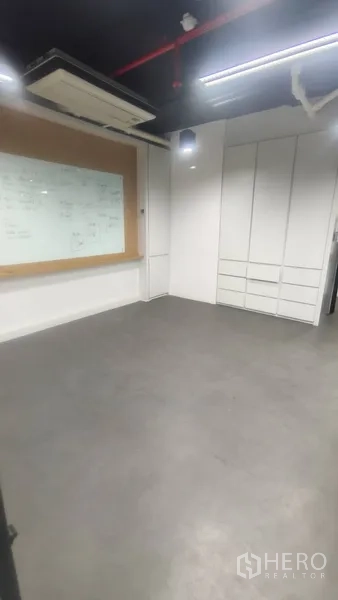 Office Space for rent in Pathum Wan, Bangkok - Private room featuring built-in cabinets and a wall-mounted whiteboard with ceiling lighting.